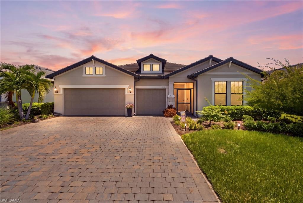Dockside Floor Plan with Stucco exterior, tiled roof, paver driveway, three-car garage, and beautiful landscaped front yard.