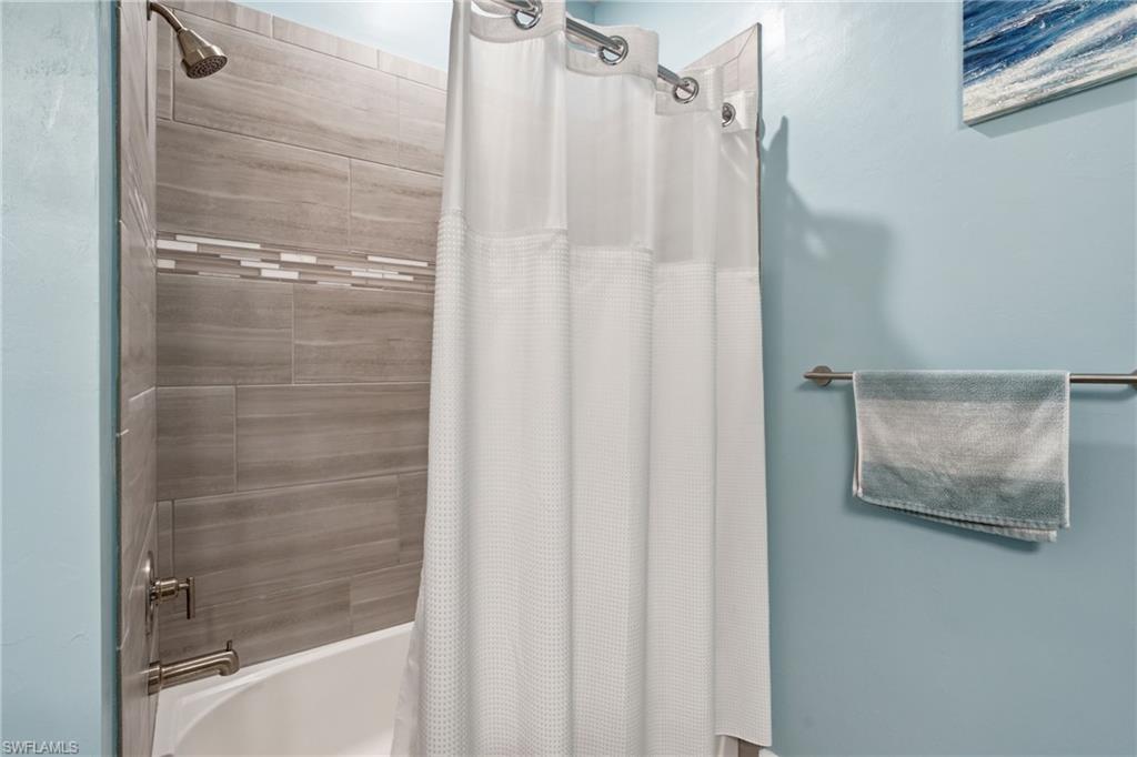 Bathtub with subway tile surround, decorative mosaic tile accent, and brushed nickel shower fixtures