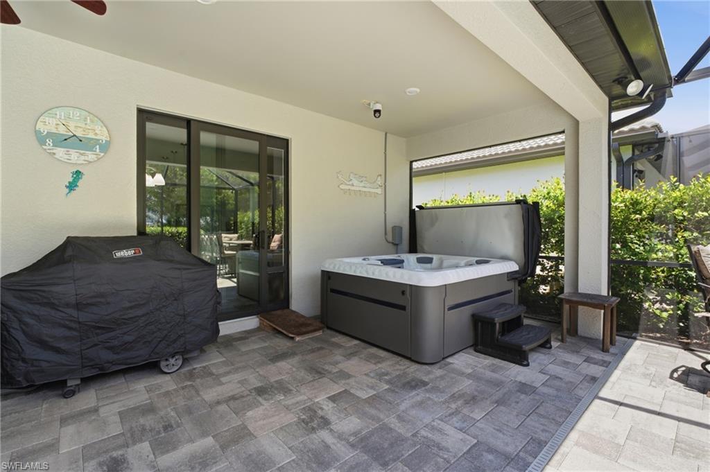Covered patio with paver flooring, built-in hot tub, and sliding glass doors