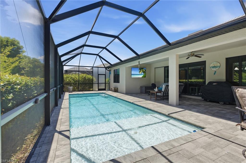 Screened enclosure with an in-ground swimming pool, paver deck, covered patio, and ceiling fan