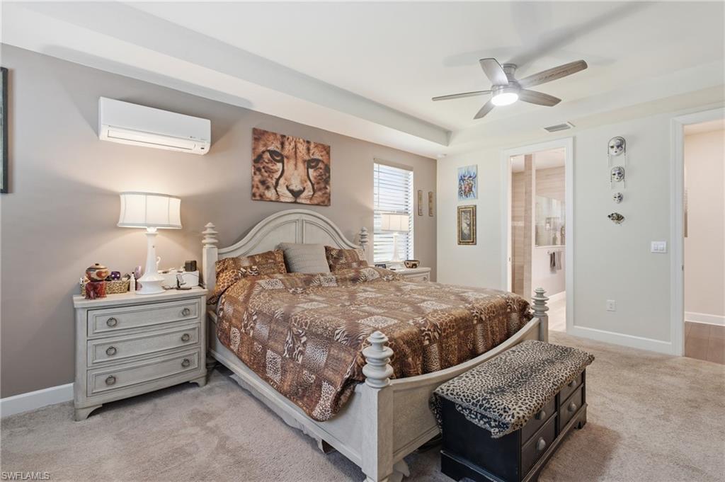 Tray ceiling, ceiling fan, split air conditioning unit, recessed lighting, and carpeted flooring