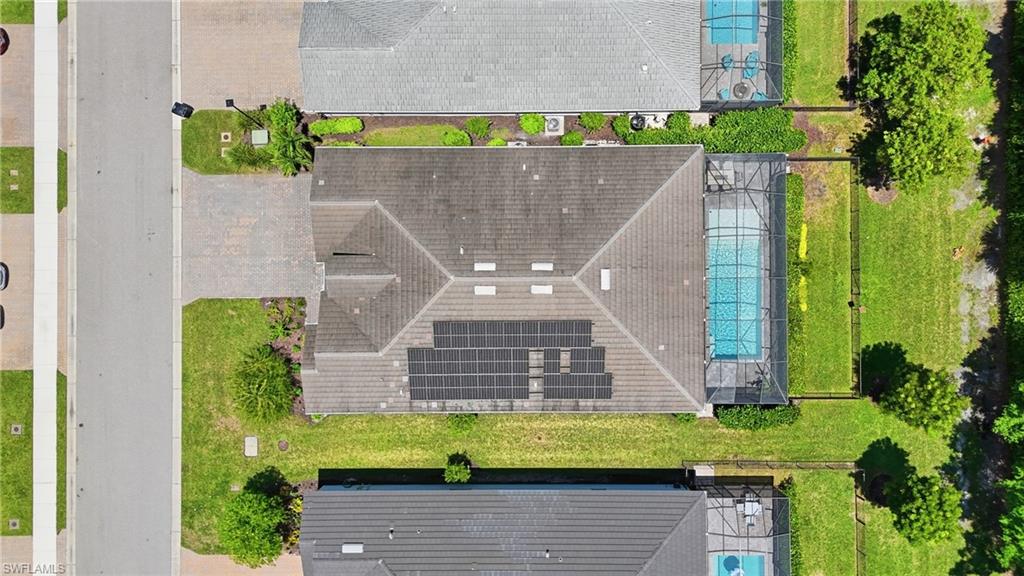 Paver driveway, solar panel array, screened swimming pool, mature perimeter landscaping, and a fenced yard