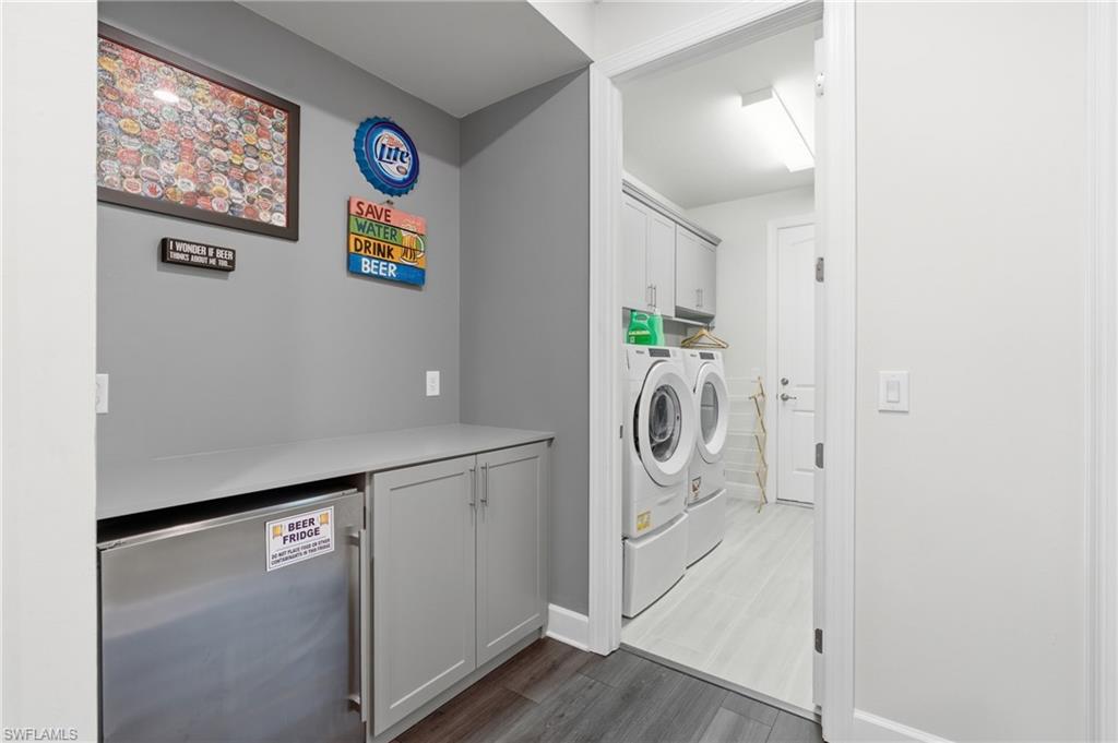 Built-in cabinetry with a grey countertop, integrated beverage refrigerator, and wood-finish flooring