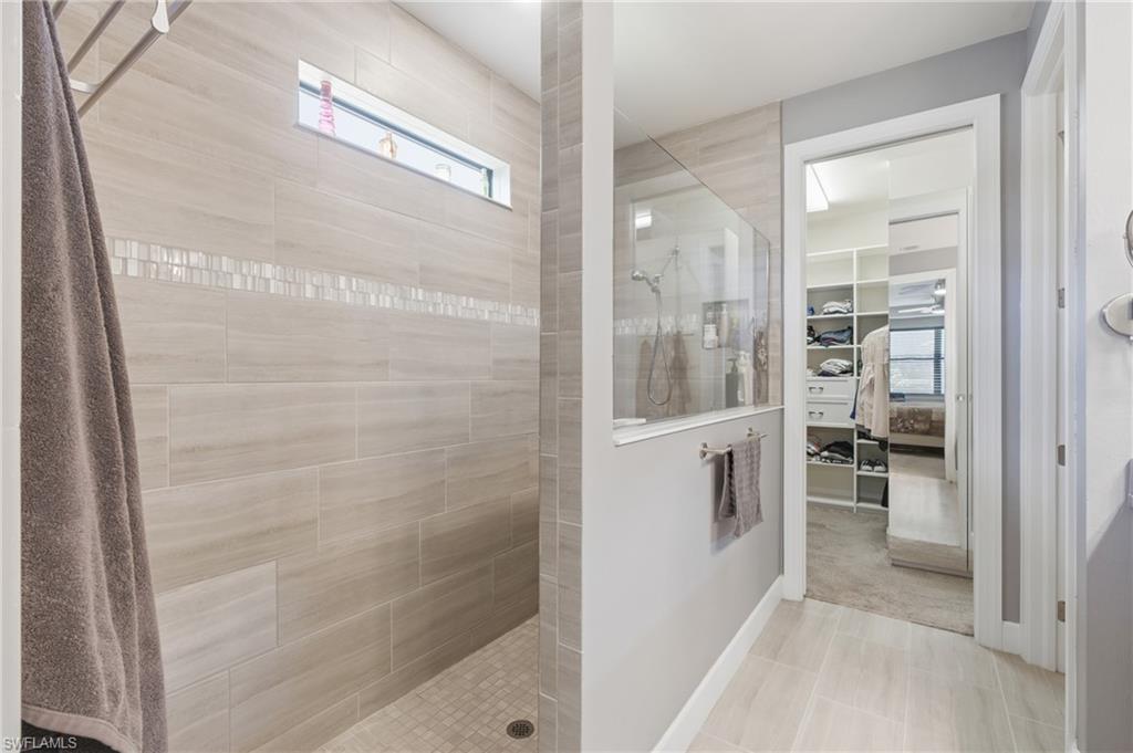 Spacious shower with large format wall tiles, mosaic accent tile, and a transom window