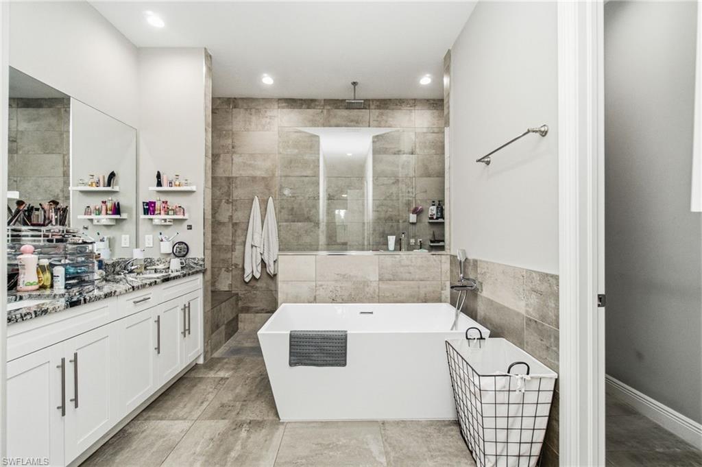 Spacious bathroom featuring a freestanding soaking tub, a walk-in shower with tile surround, and a double vanity with stone countertop