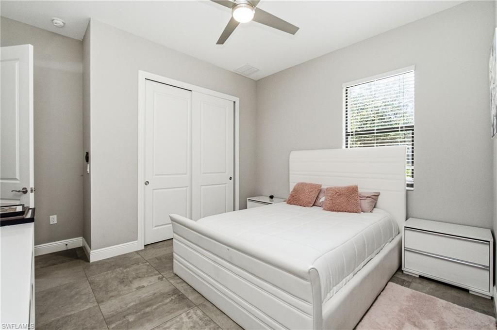 Overhead ceiling fan, window with blinds, double sliding closet doors, and tile flooring