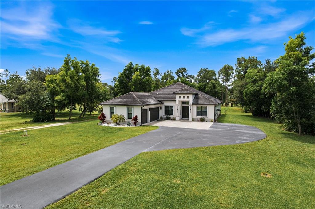 Single-story residence featuring a dark tile roof, white exterior, and prominent entry with dark double doors