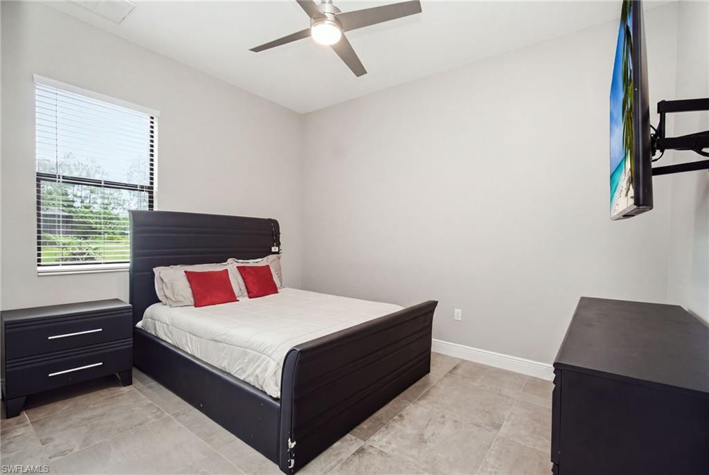 Tile flooring, window with horizontal blinds, overhead ceiling fan, neutral wall tones, and a wall-mounted television bracket