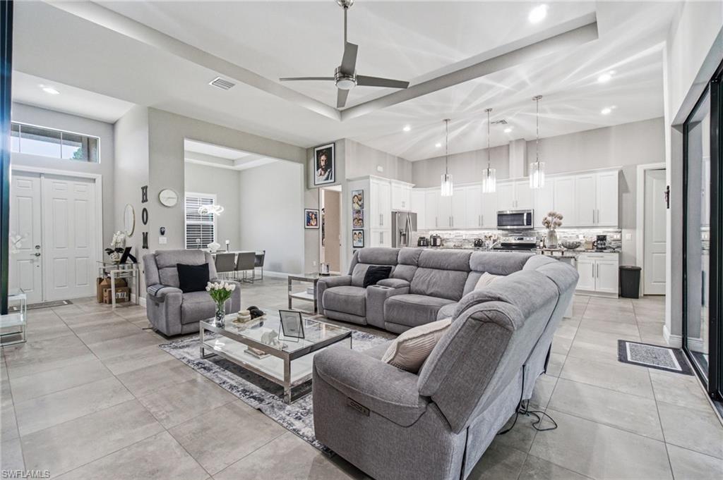 Open-concept living space featuring high ceilings with tray details, recessed lighting, and tile flooring