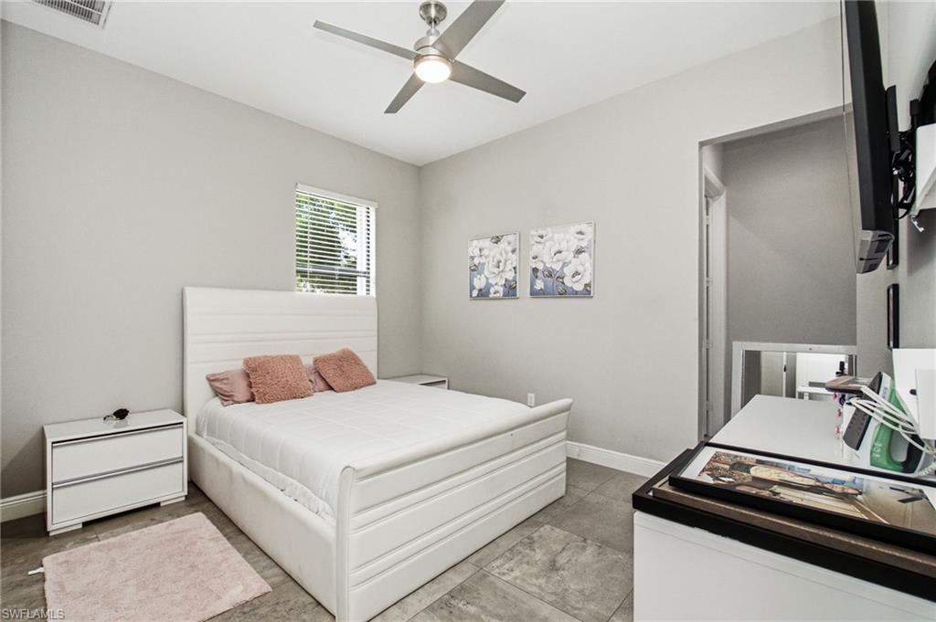 Recessed window with blinds, ceiling fan with integrated lighting, and tile flooring