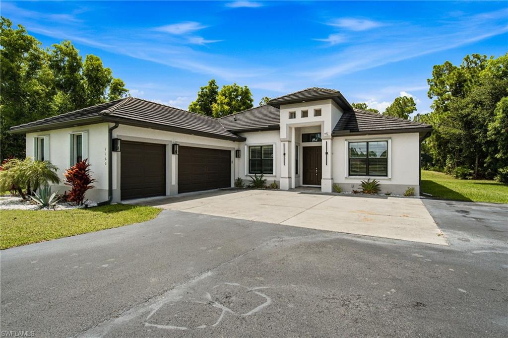 Contemporary exterior with a dark tile roof, white stucco facade, and two-car garage with dark wood-finish doors