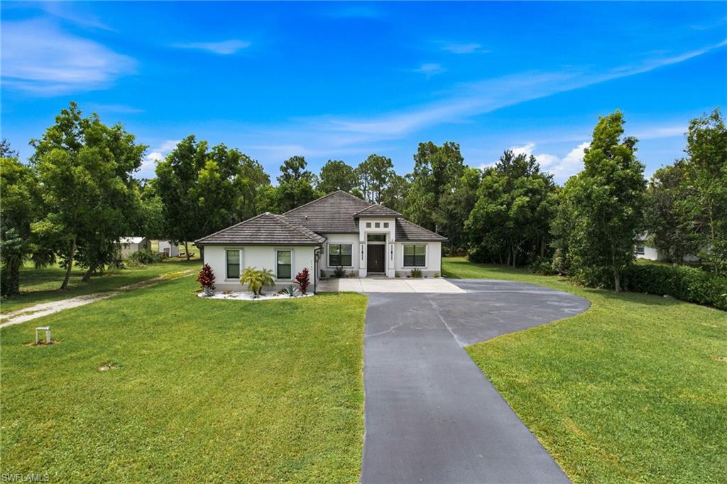 Contemporary-style residence with a dark-toned roof, light-colored exterior, and an expansive paved driveway