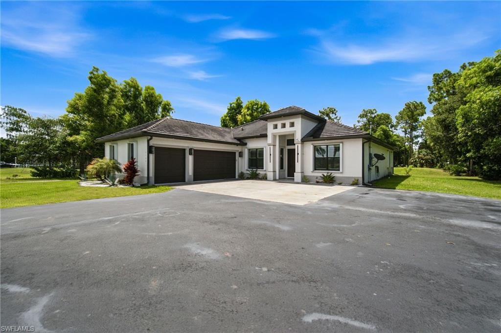 Contemporary stucco exterior with a prominent entry, attached two-car garage, and a broad asphalt driveway