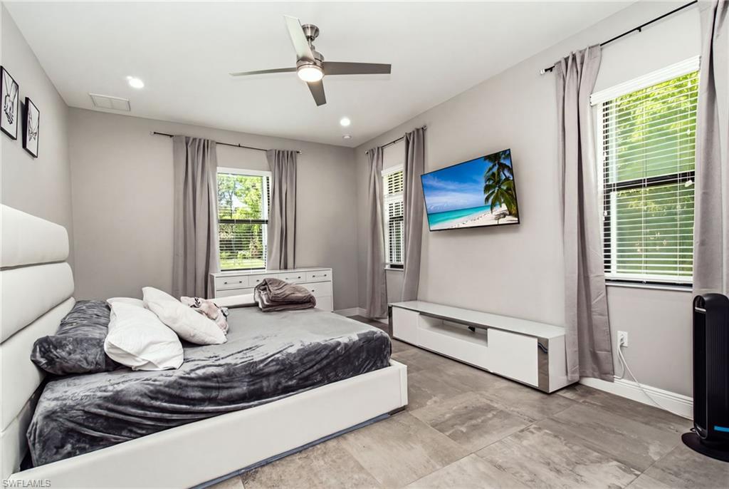 Recessed lighting, wood-finish flooring, two windows with blinds, built-in media console, and a ceiling fan with integrated lighting