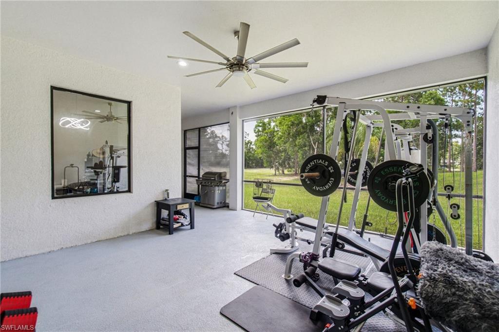 Screened enclosure with a ceiling fan, textured walls, and a reflective panel