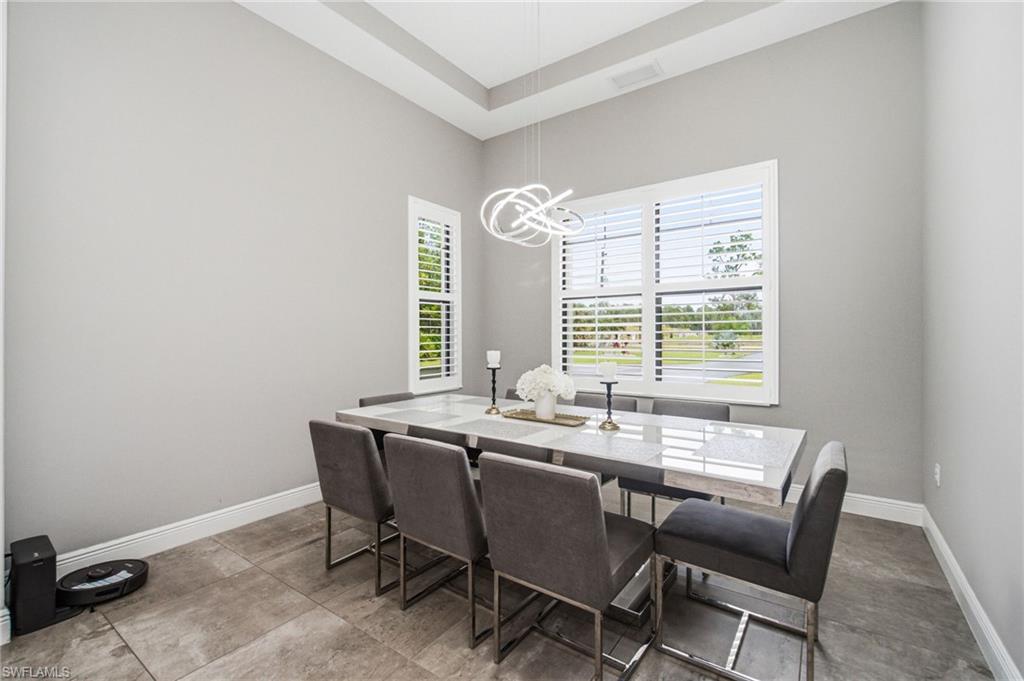 Tray ceiling, contemporary chandelier, plantation shutters, large windows, tile flooring