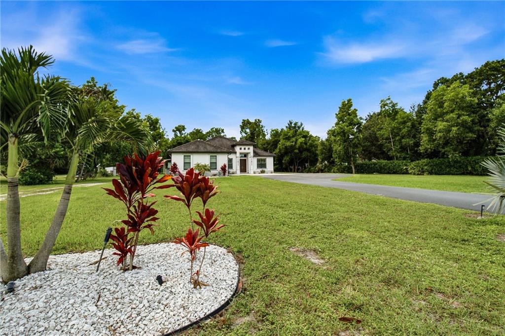 Expansive lawn with mature landscaping, a paved driveway, and a contemporary white exterior