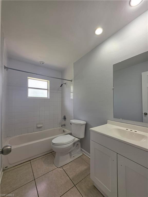 White subway tile shower surround, integrated bathtub, white vanity with an integrated sink, and recessed lighting
