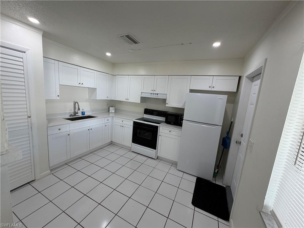 Kitchen featuring white cabinetry, a black sink with a gooseneck faucet, white appliances, and tiled flooring