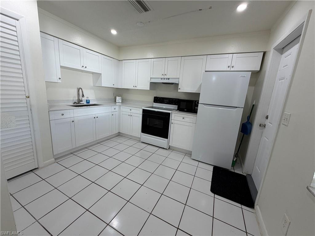 Kitchen featuring white cabinetry, a stainless steel sink with a high-arc faucet, and a range with an overhead microwave