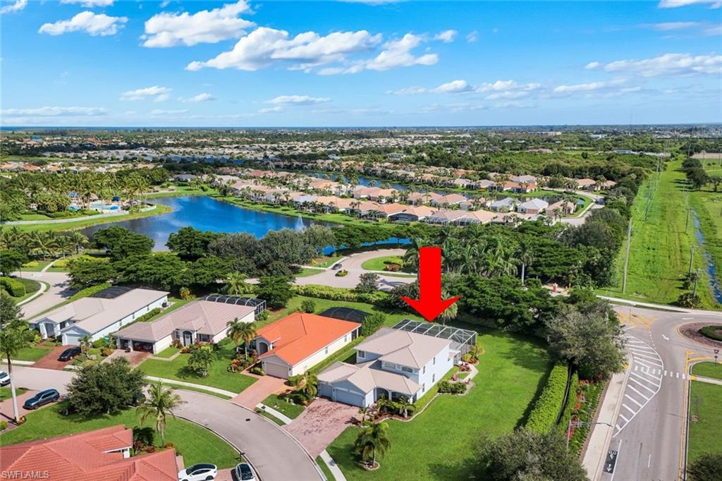 Aerial view showcasing this residence situated on expansive grounds with mature landscaping, manicured lawn, and resort-style amenities including an in-ground pool and spa