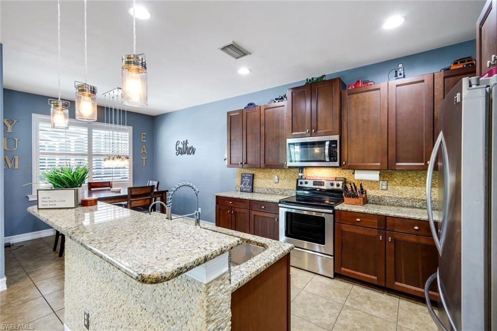 Kitchen featuring granite countertops, stainless steel appliances, dark wood cabinetry, and recessed lighting