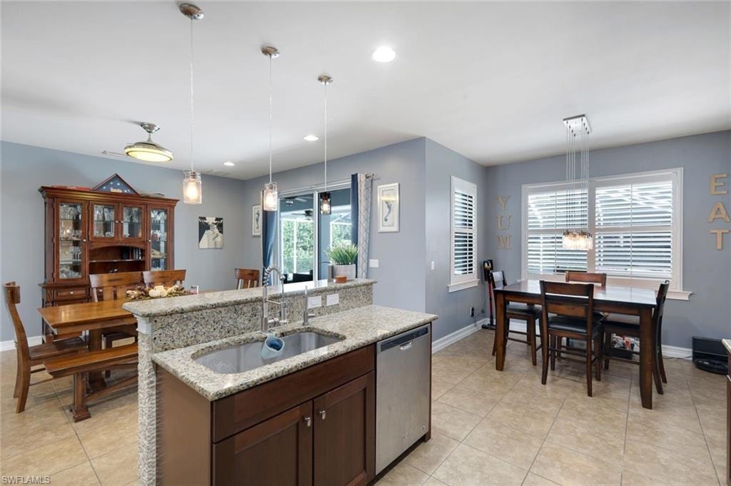 Kitchen island with granite countertops, stainless steel sink, and pendant lighting