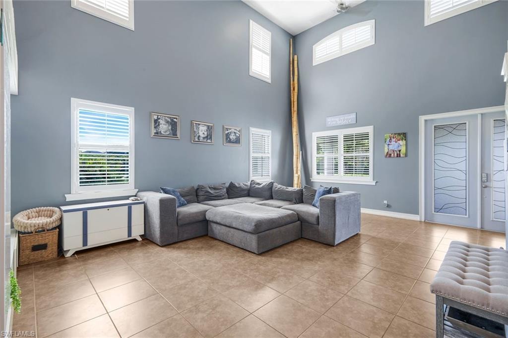 Vaulted ceiling design with high windows, tile flooring, and white plantation shutters throughout