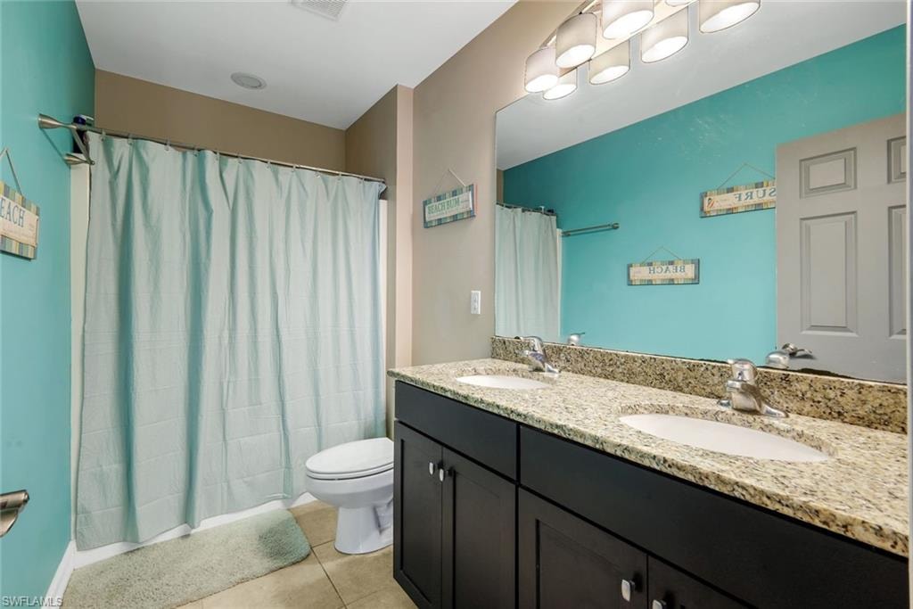 Dual vanity with stone-finish countertop, undermount sinks, and dark wood-finish cabinetry