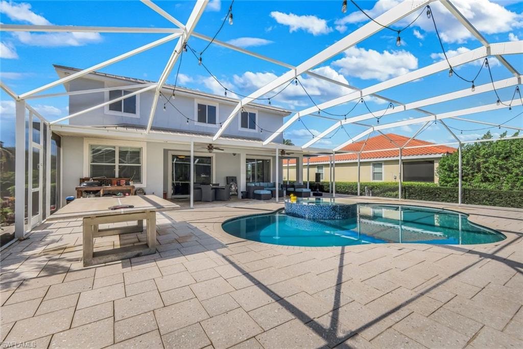 Expansive screened-in patio featuring a custom-shaped swimming pool with a mosaic-tiled spa, complemented by a surrounding paver-stone deck