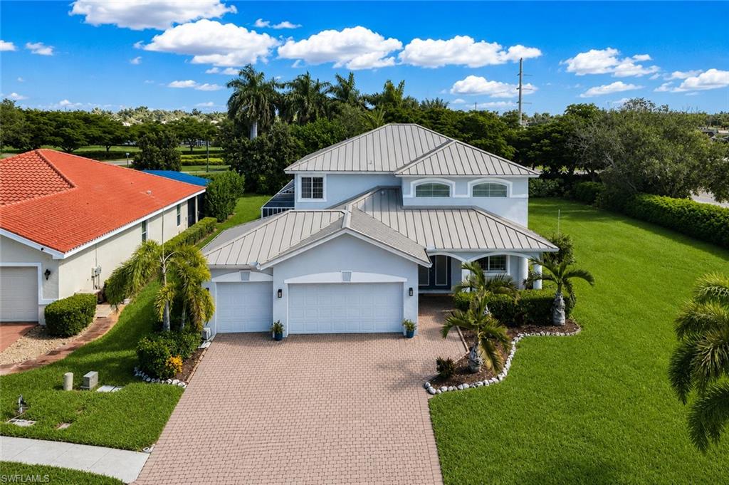 Two-story residence featuring a metal roof, an attached two-car garage, and a paver driveway