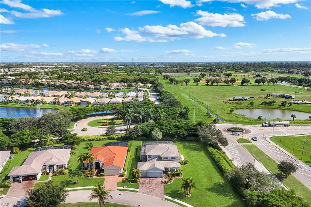 Residential community featuring a lake with a central fountain, lush green landscaping, and mature palm trees