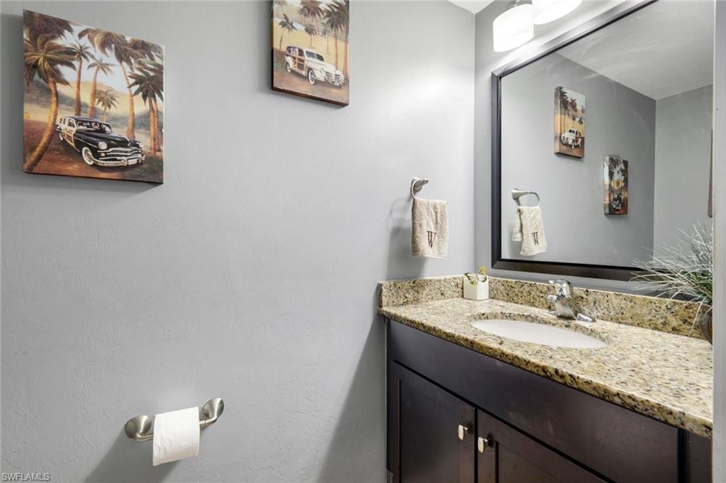 Granite countertop, undermount sink, dark wood-finish vanity, and a framed mirror