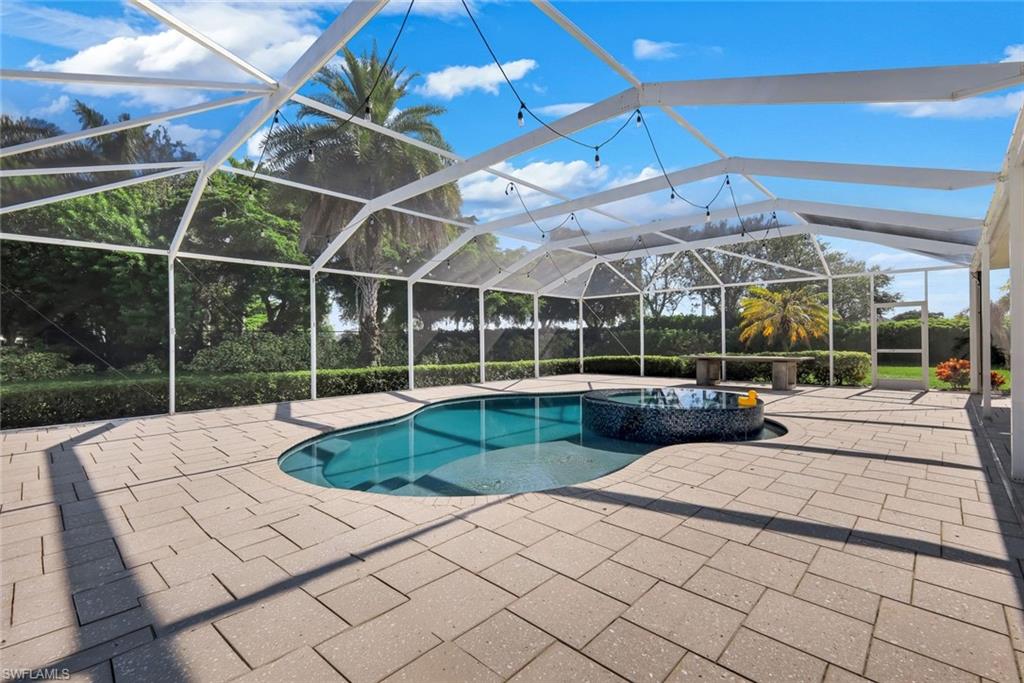 Screened-in outdoor area featuring a swimming pool, integrated spa with mosaic tile, and expansive paver patio