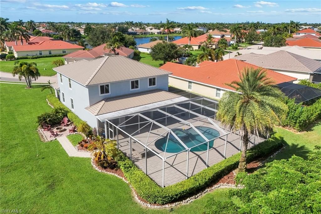 Two-story exterior with a metal roof, screened-in pool enclosure, paver patio, and a dedicated fire pit area