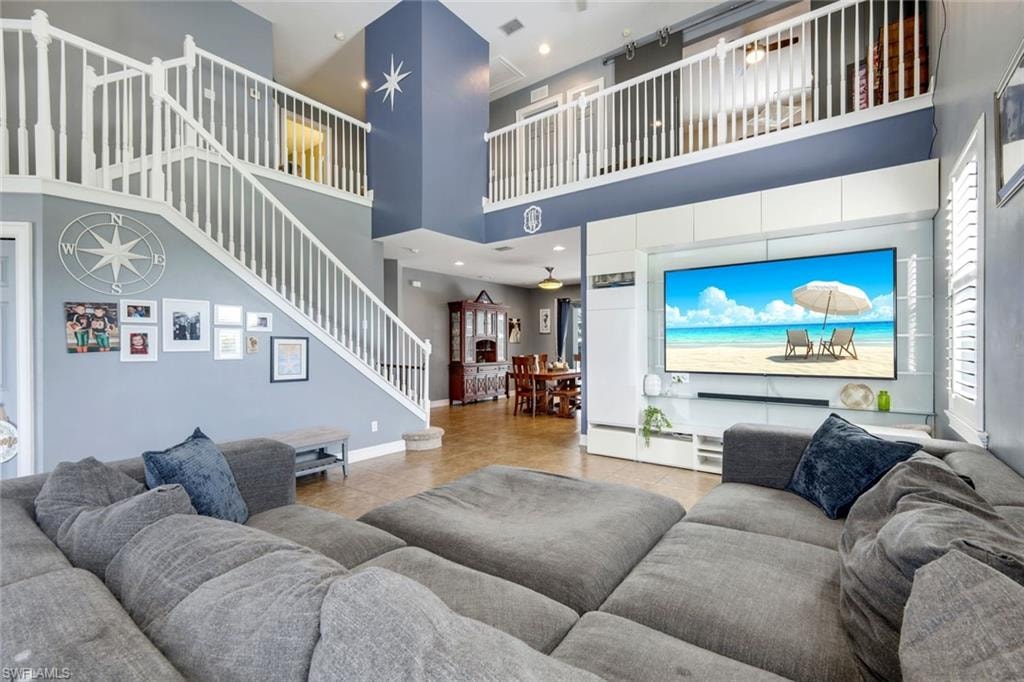 Two-story living area featuring a prominent staircase with white balusters, a built-in media center, and tile flooring