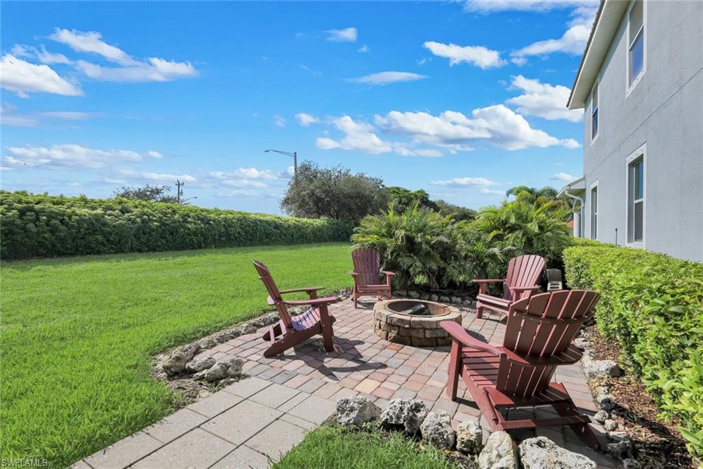 Expansive lawn with a stone paver patio featuring a built-in fire pit