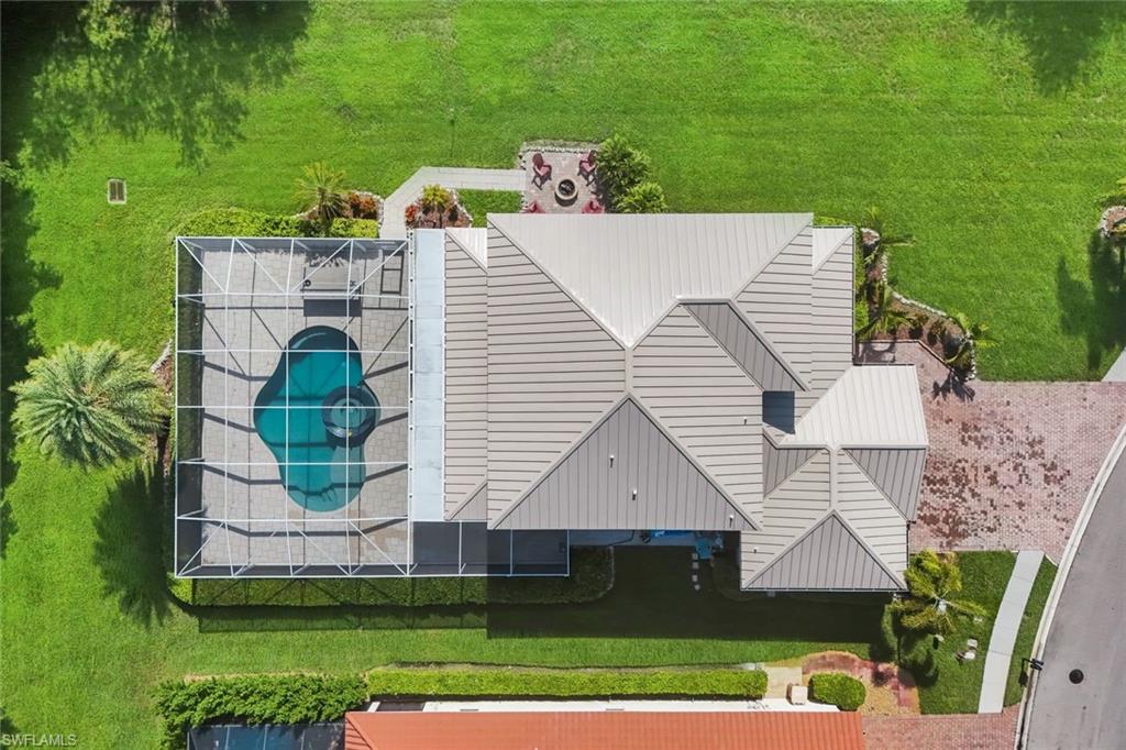 Screened-in pool with a unique shape, expansive green lawn, and a large multi-gabled roofline