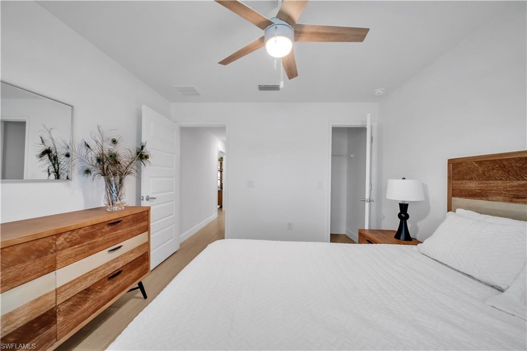 Wood-finish flooring, white walls, and a ceiling fan with light fixture