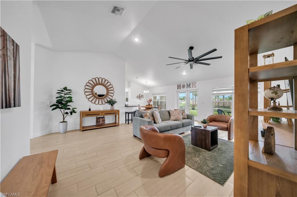Vaulted ceilings with recessed lighting, large format tile flooring, modern ceiling fan, and French doors to the outdoor area