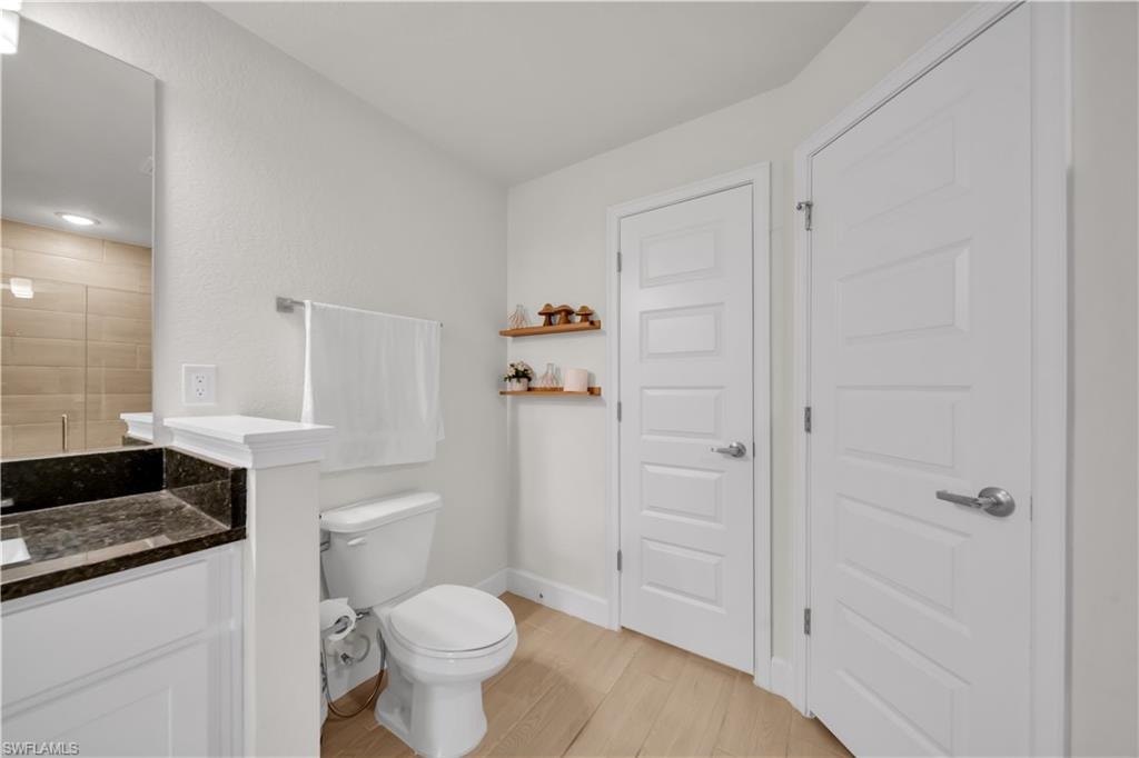 White vanity with dark stone countertop and integrated sink, chrome faucet, and mirrored medicine cabinet