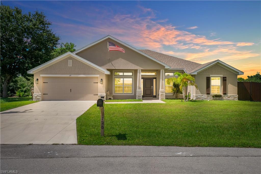 Stucco exterior with stone accents, a two-car garage, a covered entry, and a paved driveway