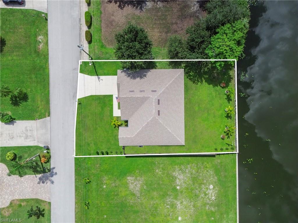 Single-story residence featuring a shingled roof, a paved driveway, and manicured green lawns
