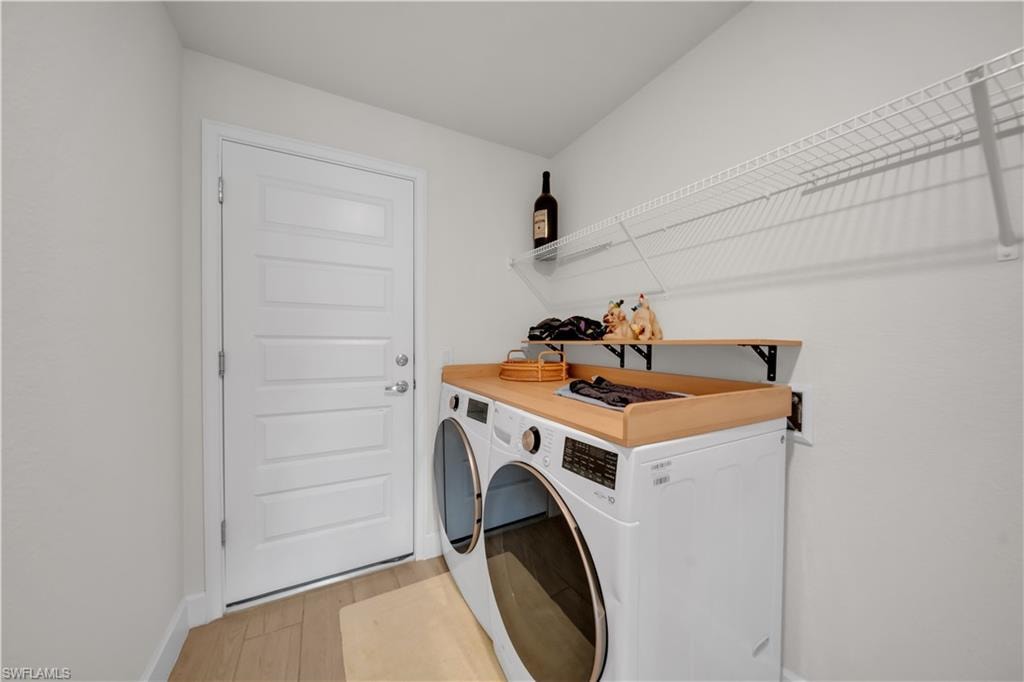 Dedicated laundry area featuring wood-finish flooring, a white paneled door, and ample wire shelving