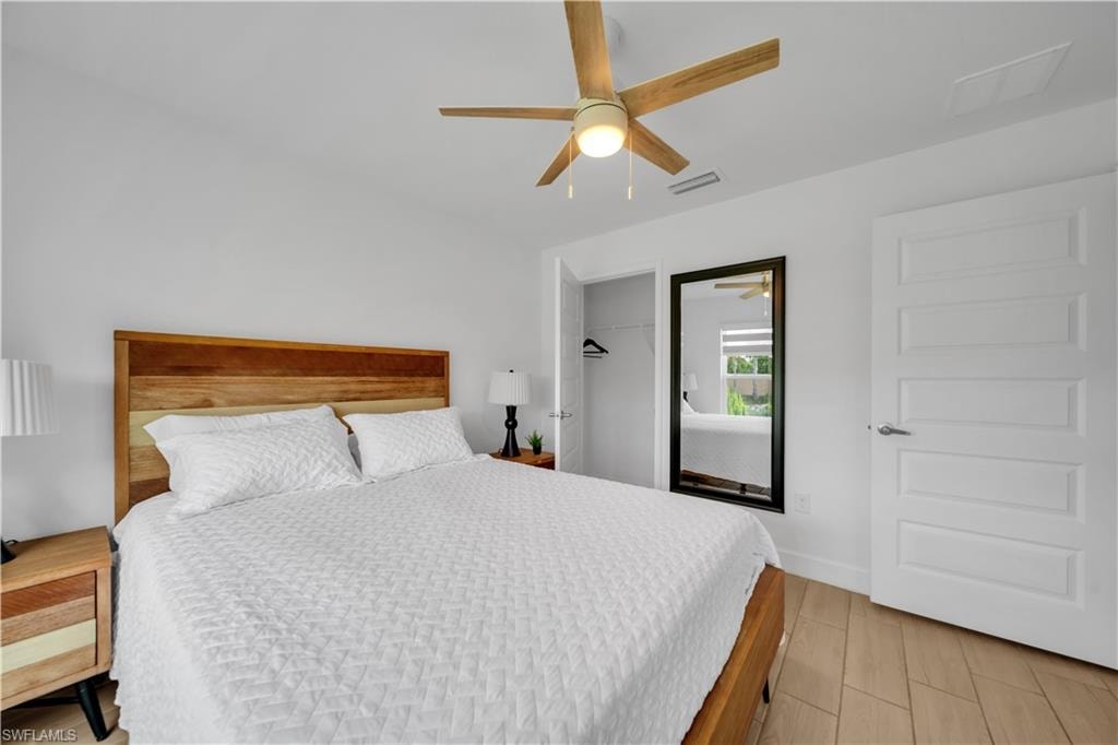 Wood-finish flooring, ceiling fan with integrated lighting, paneled interior door, and a built-in closet with hanging rod