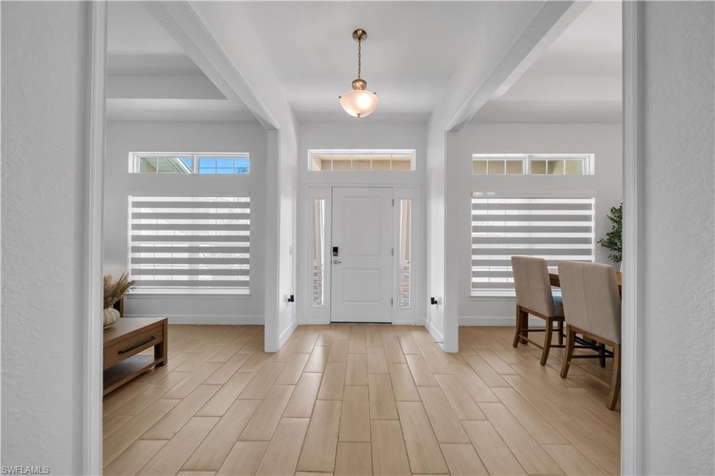 Entryway featuring wood-finish flooring, a pendant light fixture, and transom windows