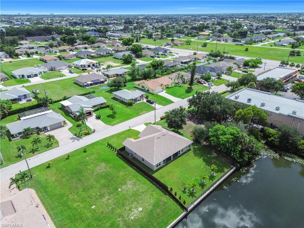 Waterfront property with a seawall, expansive green lawn, and surrounding residential neighborhood