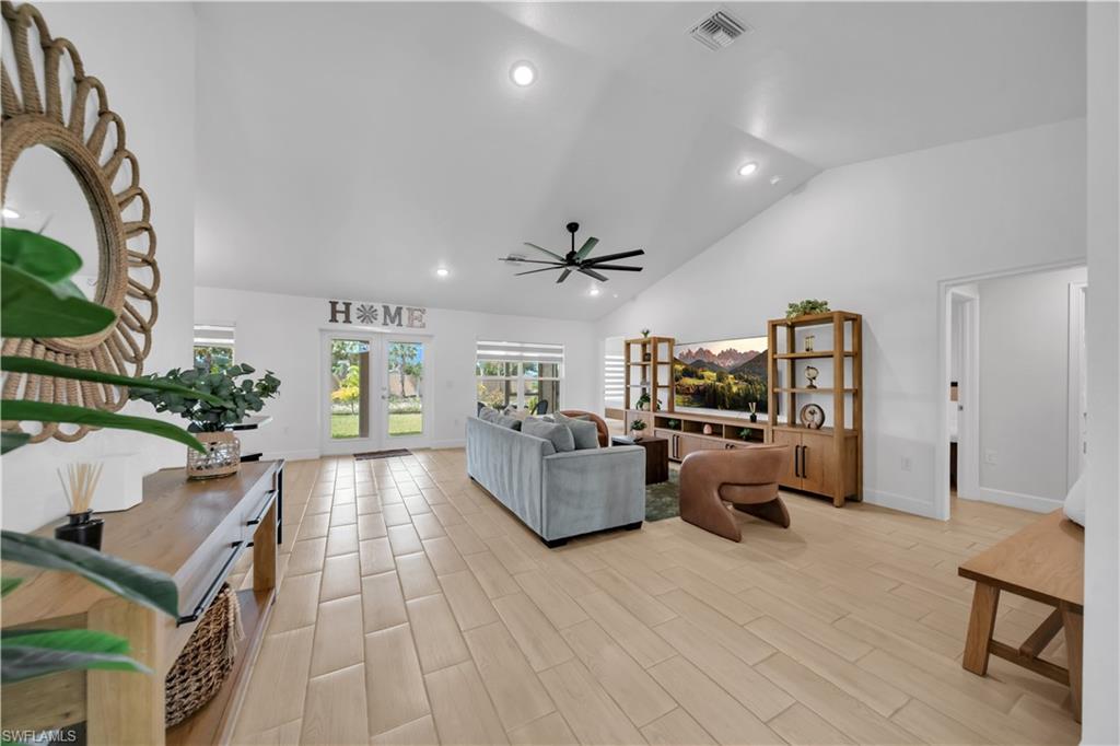 Vaulted ceiling, recessed lighting, ceiling fan, wood-finish flooring, and French doors to exterior