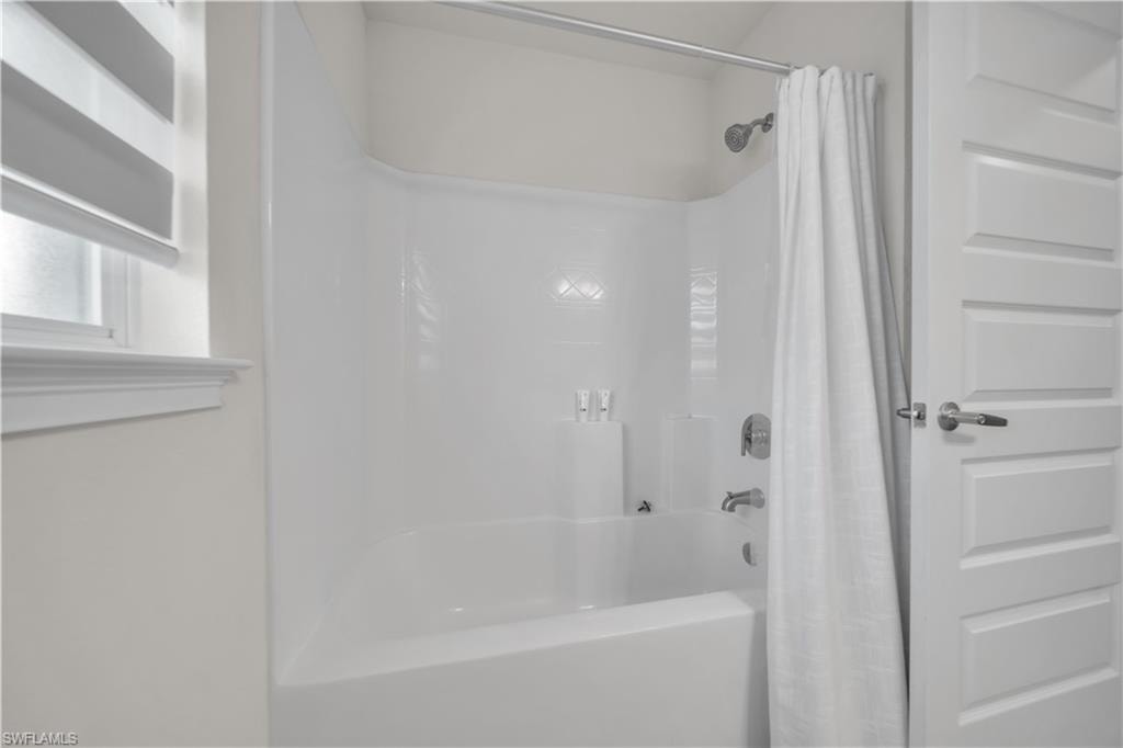 White tub and shower combination with chrome fixtures and an adjacent paneled door