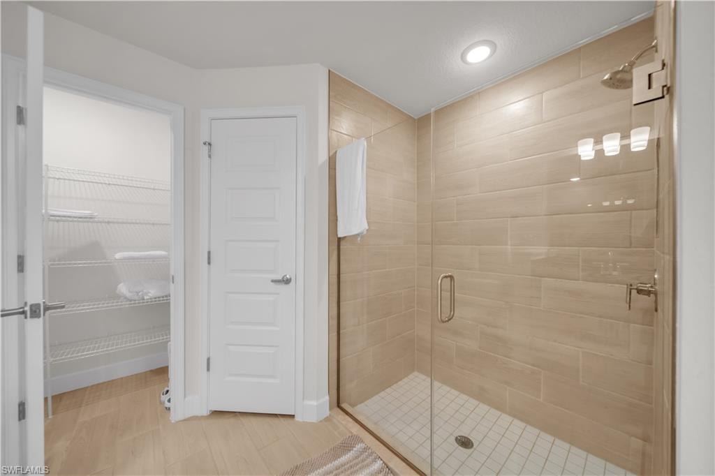 Glass-enclosed shower with subway tile surround, recessed lighting, and a rainfall showerhead